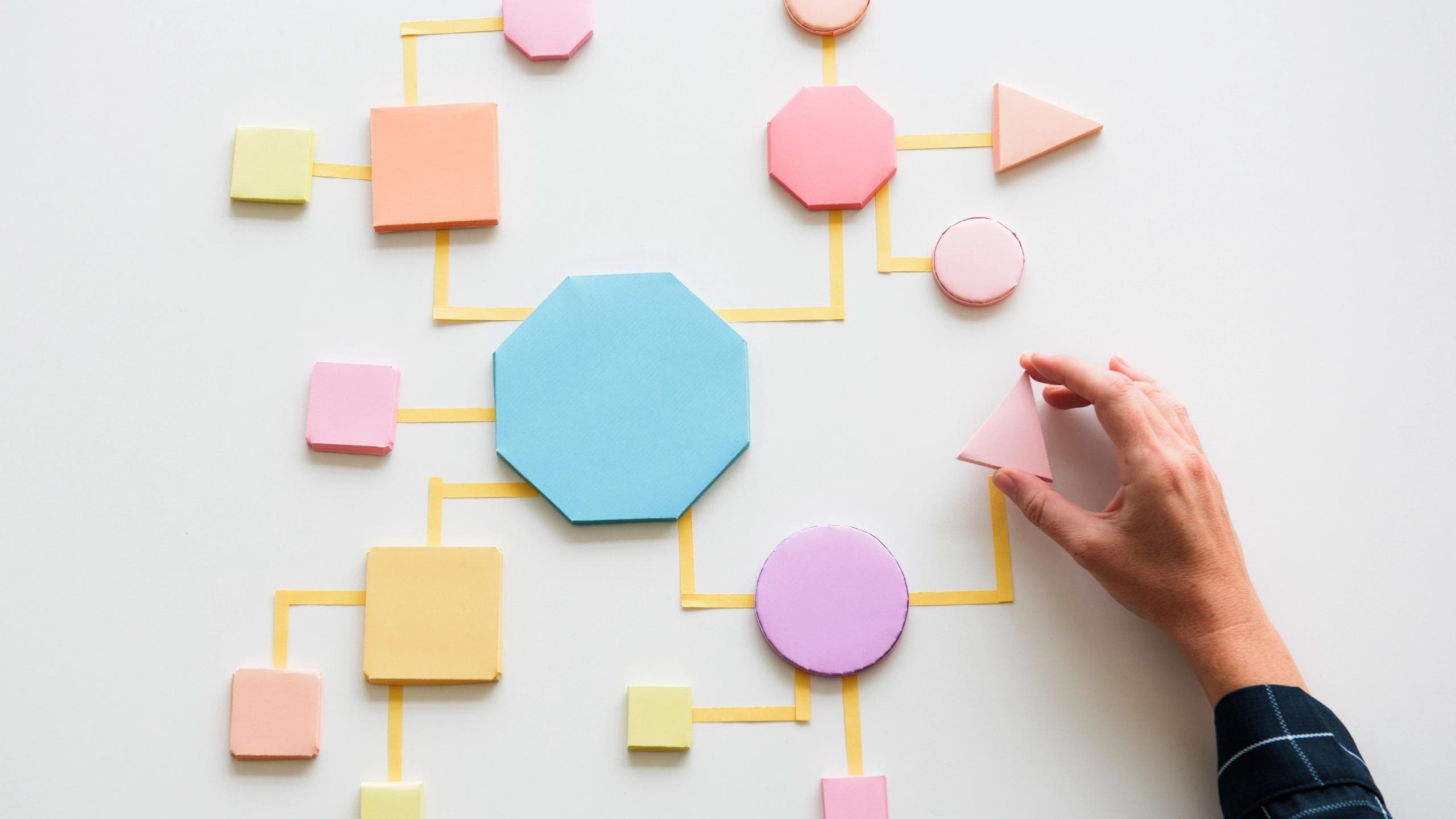 A visual flow of connected shapes representing user journeys and decision paths, with a hand adjusting one element to show how underlying experience structure and surface interface design work together to shape usability and outcomes.